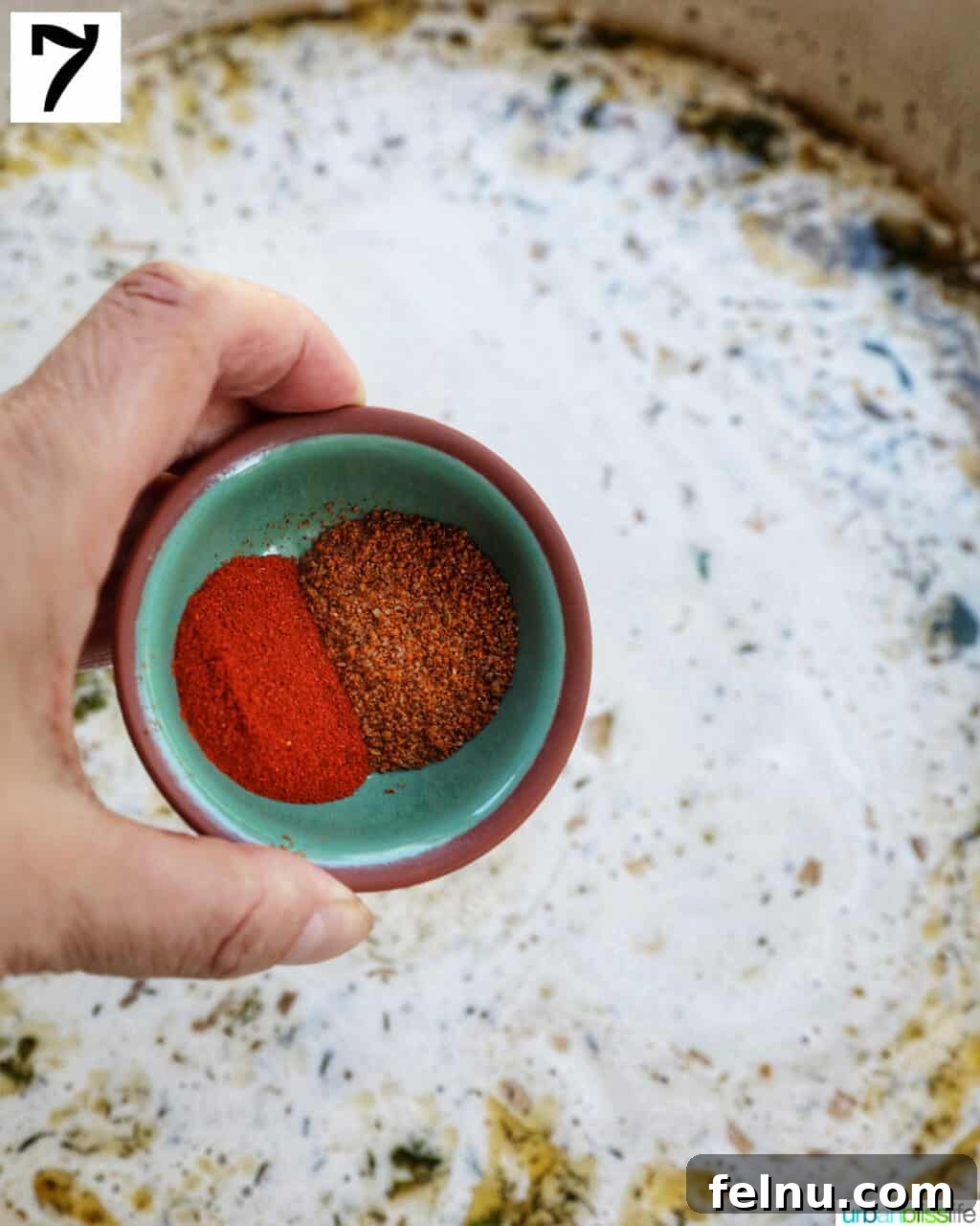 Adding Old Bay Seasoning, paprika, salt, and pepper to the sauce.