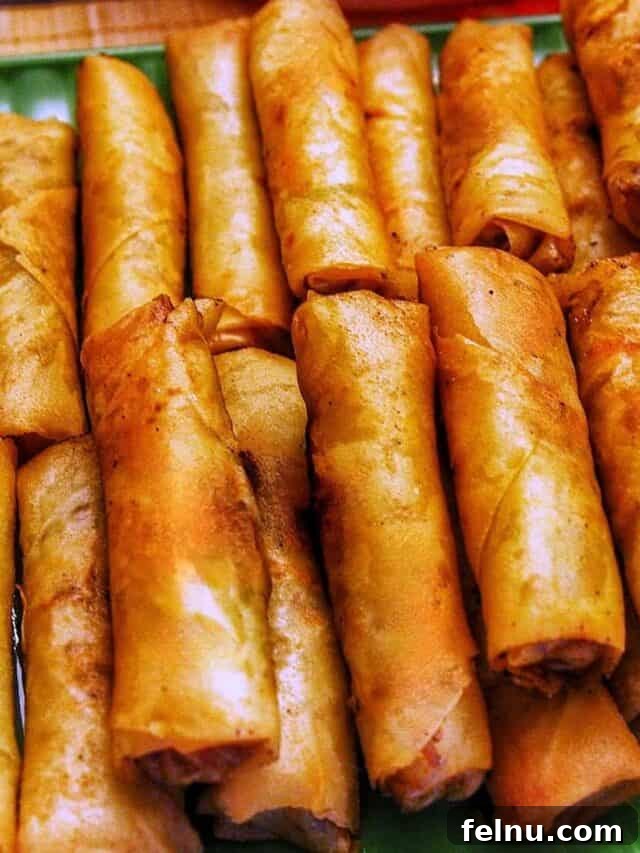 Dinner with the Jayme-Schotlands 13 A tray of golden-brown Filipino lumpia (savory spring rolls) perfectly stacked on top of one another, freshly fried and ready to be enjoyed as a popular appetizer.