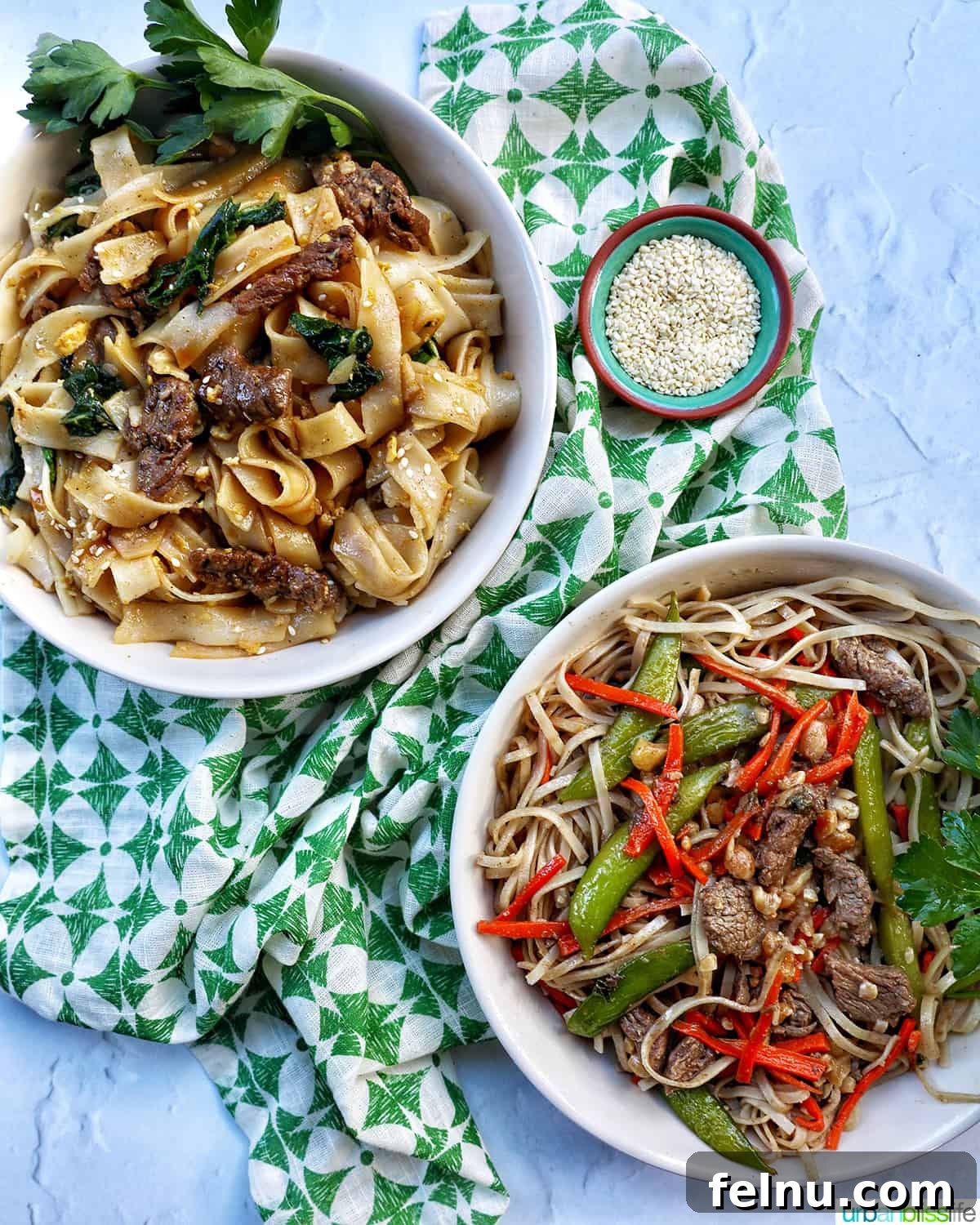 Pad See Ew Versus Pad Thai Your Ultimate Noodle Showdown 2 Two bowls of Thai noodles, one Pad See Ew and one Pad Thai, displayed on a green patterned napkin with sesame seeds.
