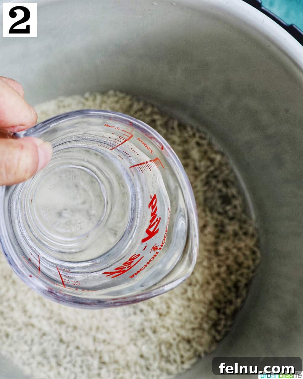 Fluffy Instant Pot Basmati Rice 6 hand holding a pyrex measuring cup of water over an instant pot pot with white rice.