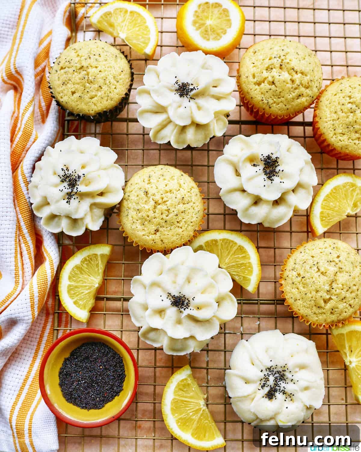 Lemon Poppy Seed Dream Cupcakes 2 Lemon poppyseed cupcakes undecorated next to cupcakes with buttercream frosting flower decorations next to lemon slices.