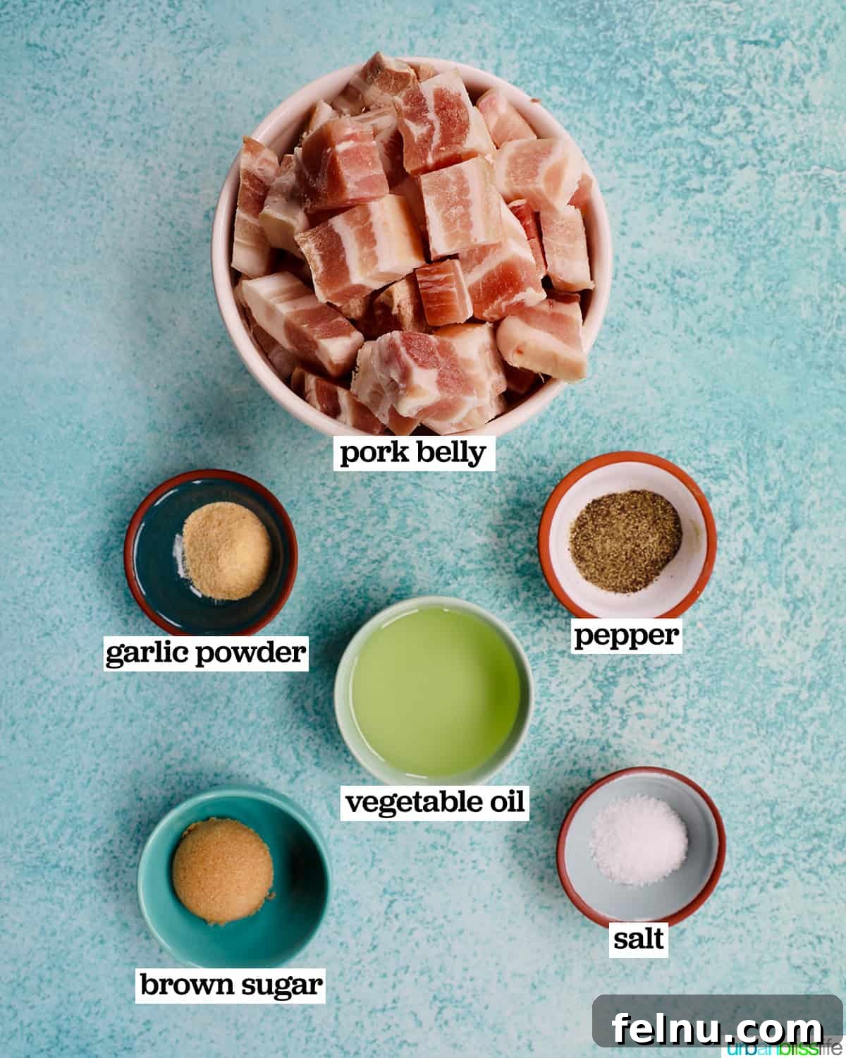 Crispy Air Fryer Pork Belly Bites 4 bowls of ingredients to make air fryer pork belly bites on a blue background.