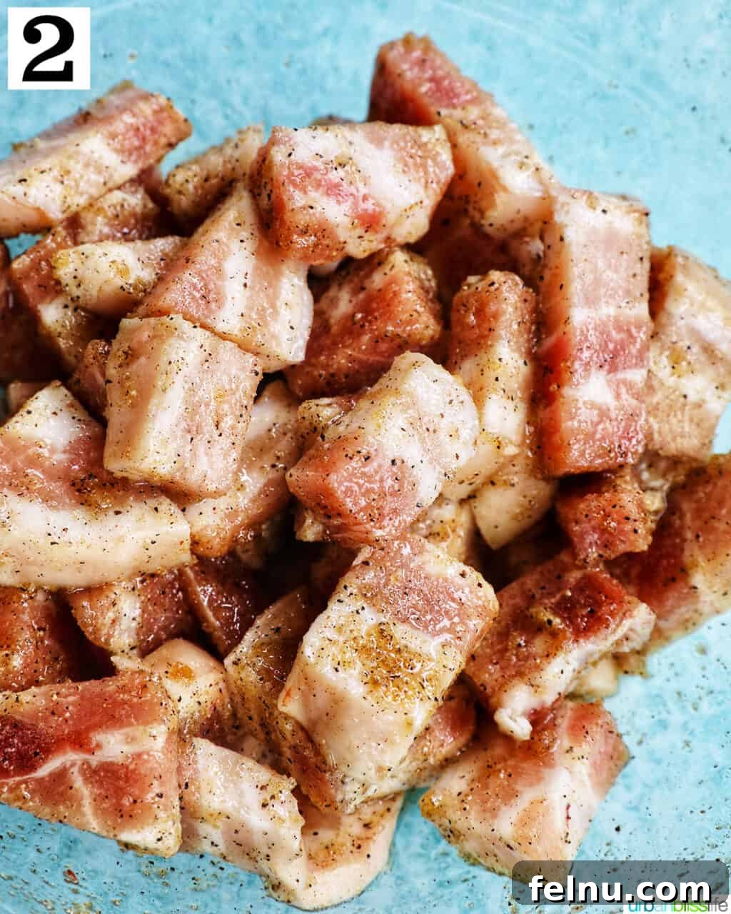 Crispy Air Fryer Pork Belly Bites 6 pork belly bites seasoned in a glass bowl over blue background.