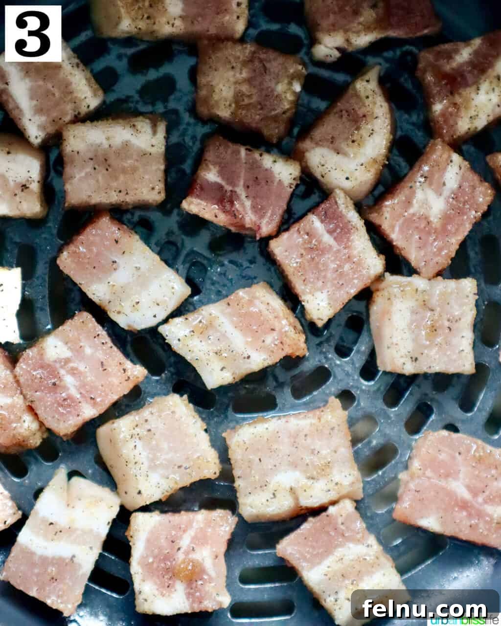 Crispy Air Fryer Pork Belly Bites 7 pork belly bites in an air fryer basket, uncooked.