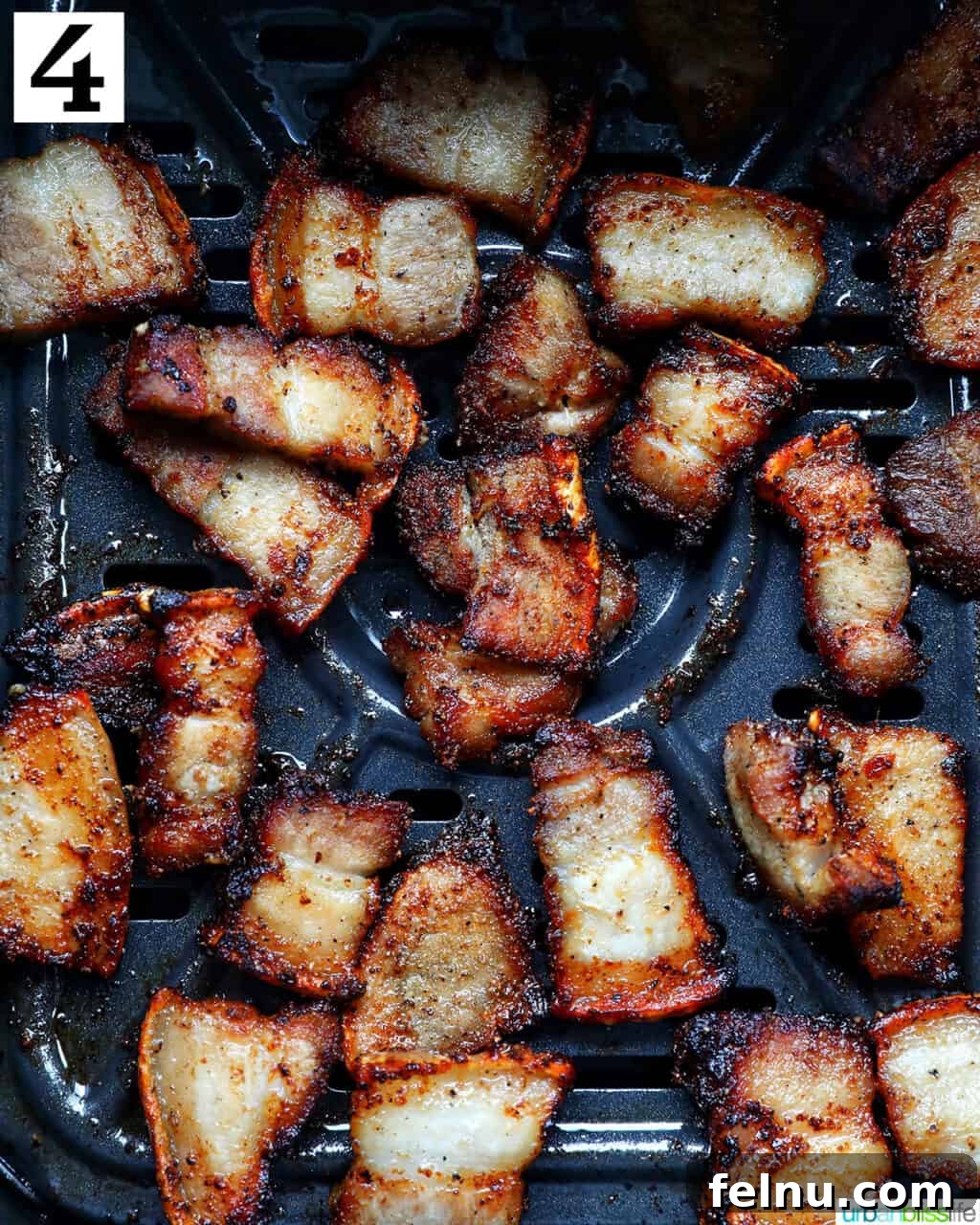 Crispy Air Fryer Pork Belly Bites 8 cooked pork belly bites in an air fryer basket.