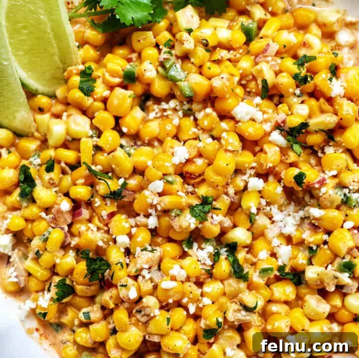 Big bowl of elote dip (Mexican corn dip) with side of lime wedges and cilantro.
