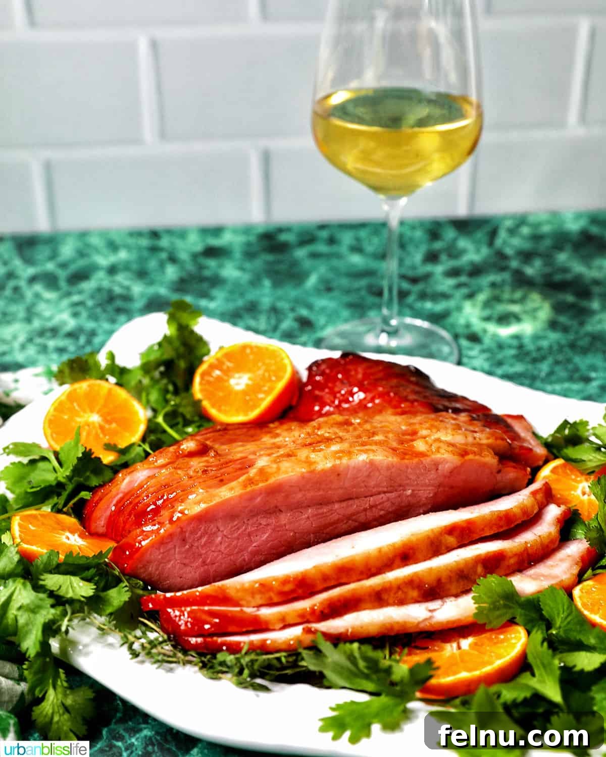 Elevate Your Ham with the Perfect Wine 2 Glass of white wine behind a platter of honey glazed ham with garnishes.