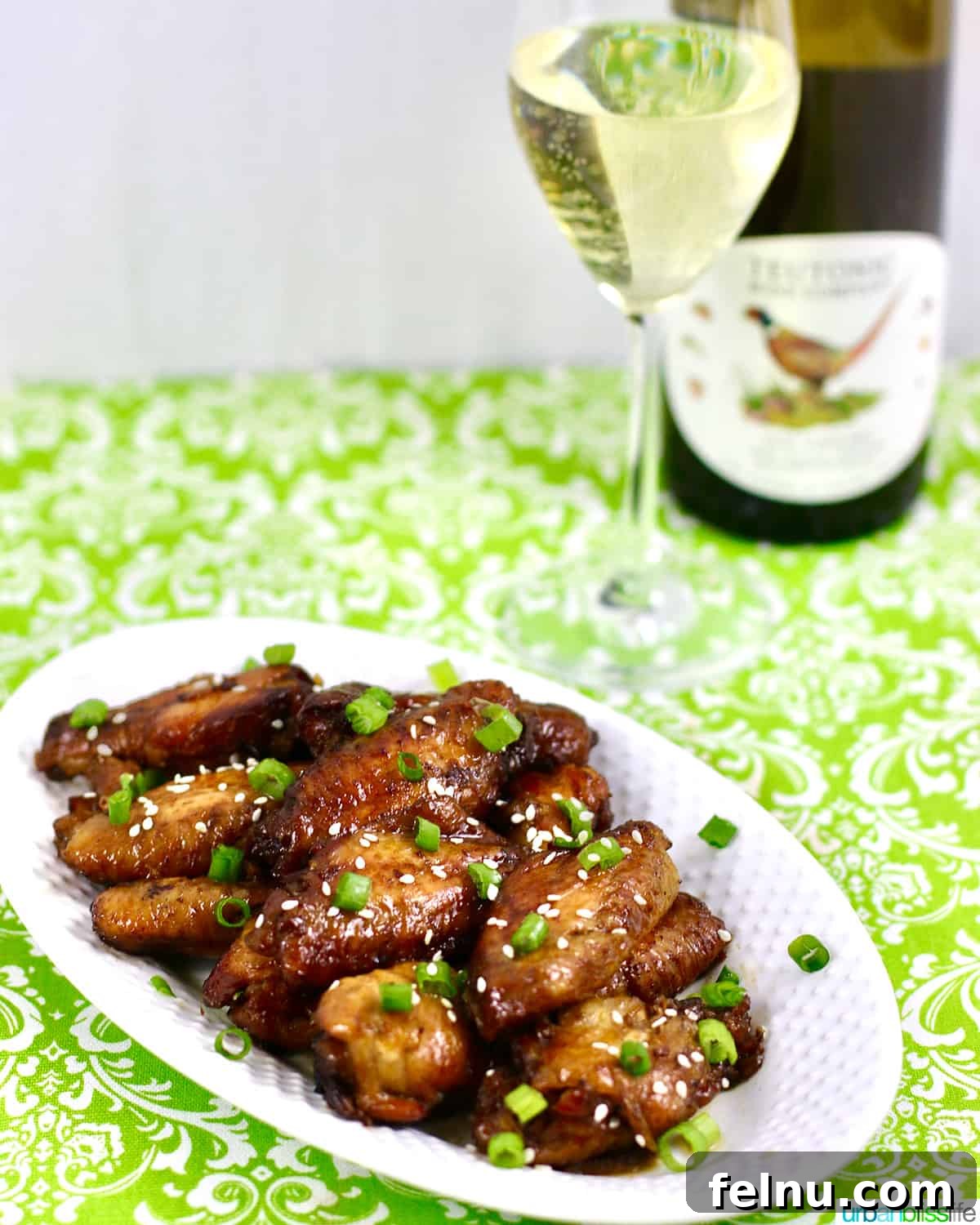 Perfect Wine Pairings for Every Chicken Dish 4 A glass of crisp Riesling wine next to a plate of savory Asian chicken wings, illustrating a perfect pairing.