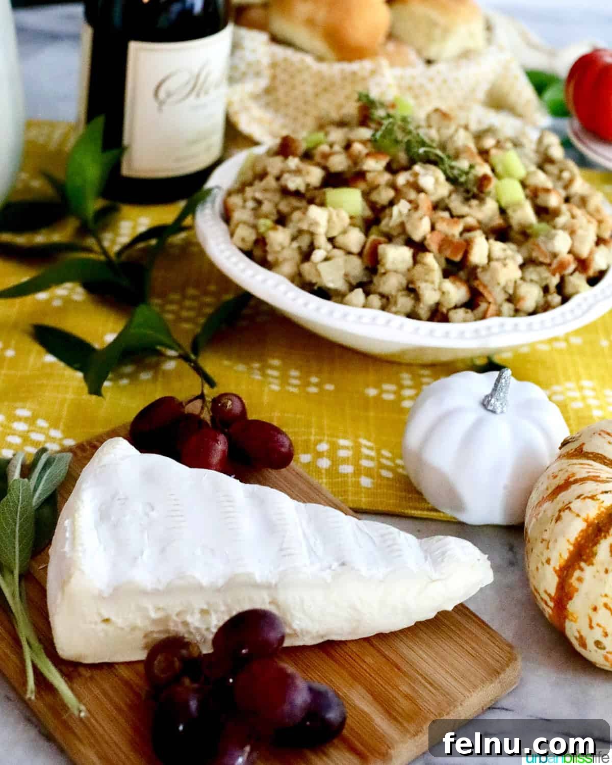 Chardonnay's Culinary Companions 13 A wedge of creamy Brie cheese rests on a board, accented with fresh grapes, with Thanksgiving stuffing gently blurred in the background.