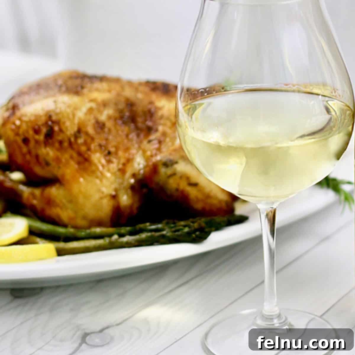 Chardonnay's Culinary Companions 6 A glass of chardonnay stands elegantly in front of a perfectly golden roast chicken.
