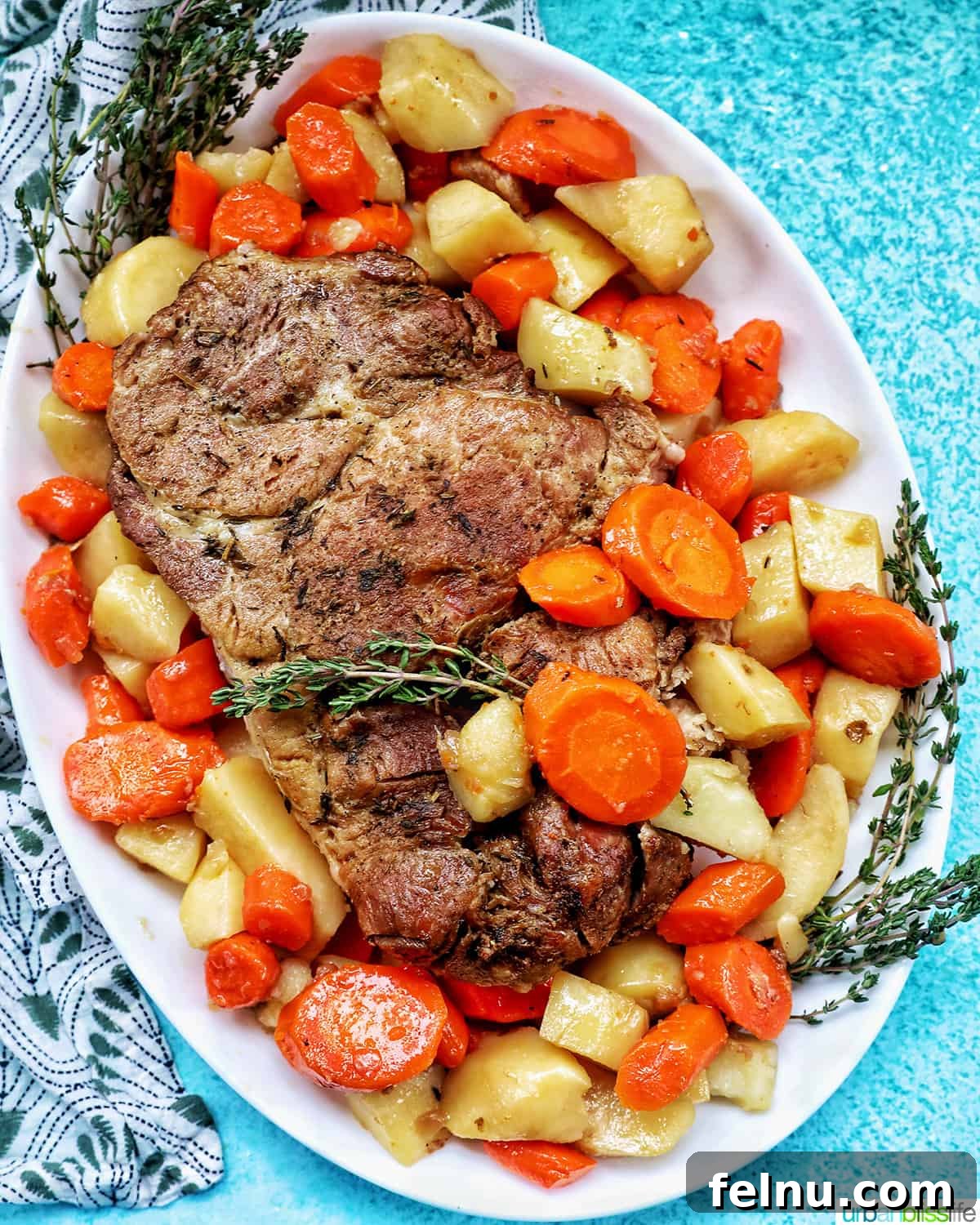Chardonnay's Culinary Companions 10 An Instant Pot pork roast, generously surrounded by chopped carrots, potatoes, and fresh herbs, presented on a white serving platter atop a blue table.