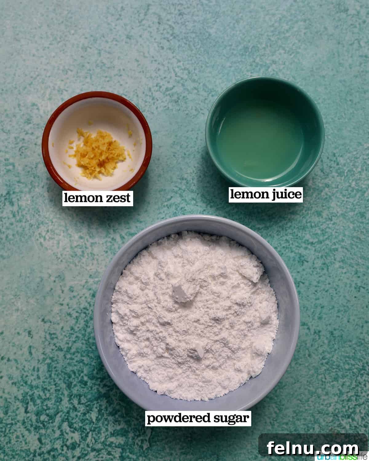 Ingredients for the lemon glaze, including powdered sugar, lemon zest, and fresh lemon juice, displayed in bowls on a blue background.