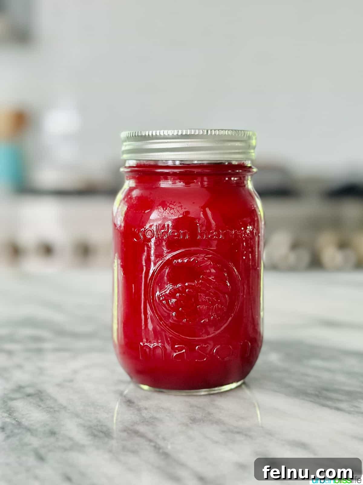 Ruby Root Revival 9 mason jar full of vibrant red beet juice on a marble countertop.