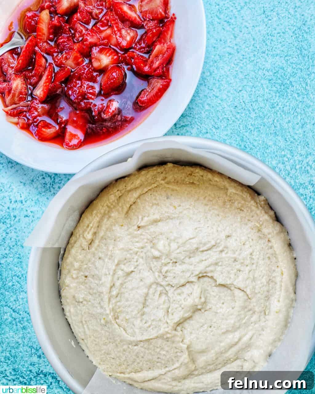 Cake pan filled with Strawberry Spoon Cake batter and a white bowl of mashed strawberries above it.