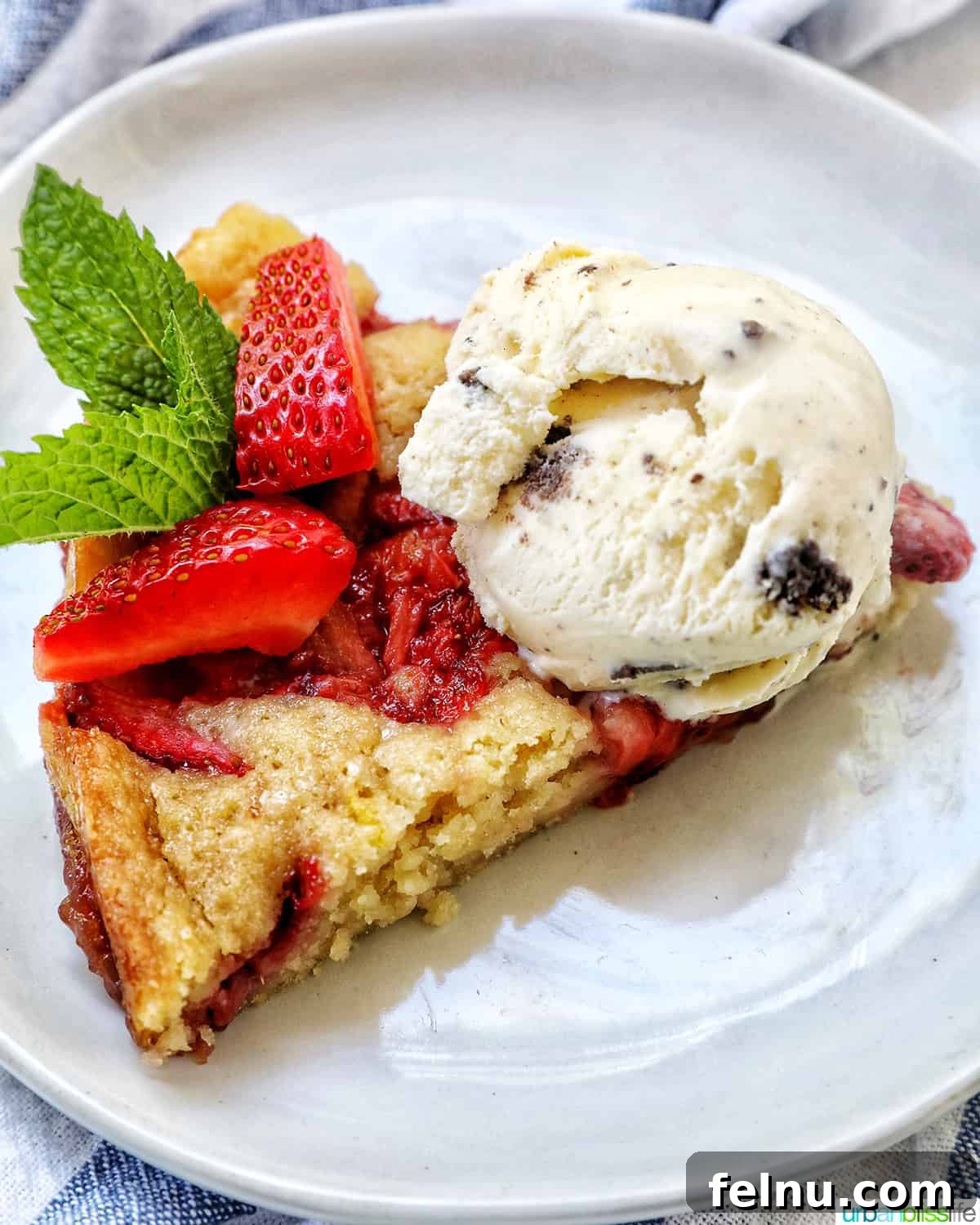 Slice of Strawberry Spoon Cake on a white plate topped with chocolate chip ice cream.