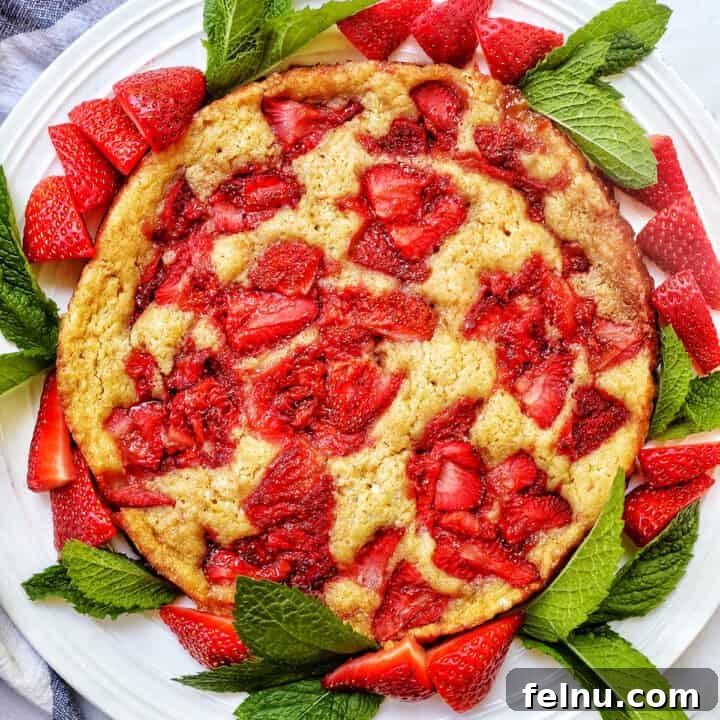 Strawberry Spoon Cake with mint leaves and sliced strawberries as garnish on a white plate.