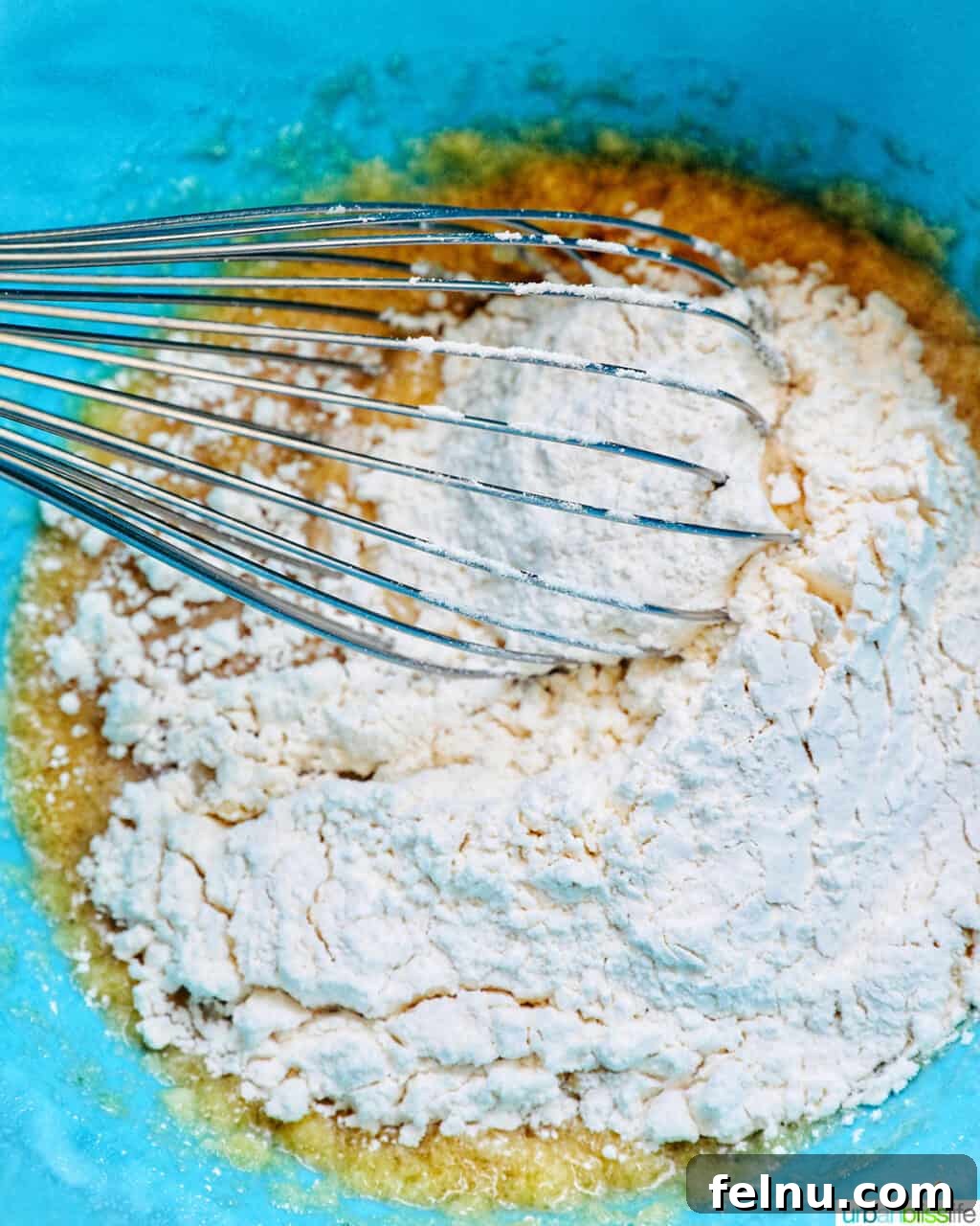 Whisk in a blue bowl of wet and dry ingredients.