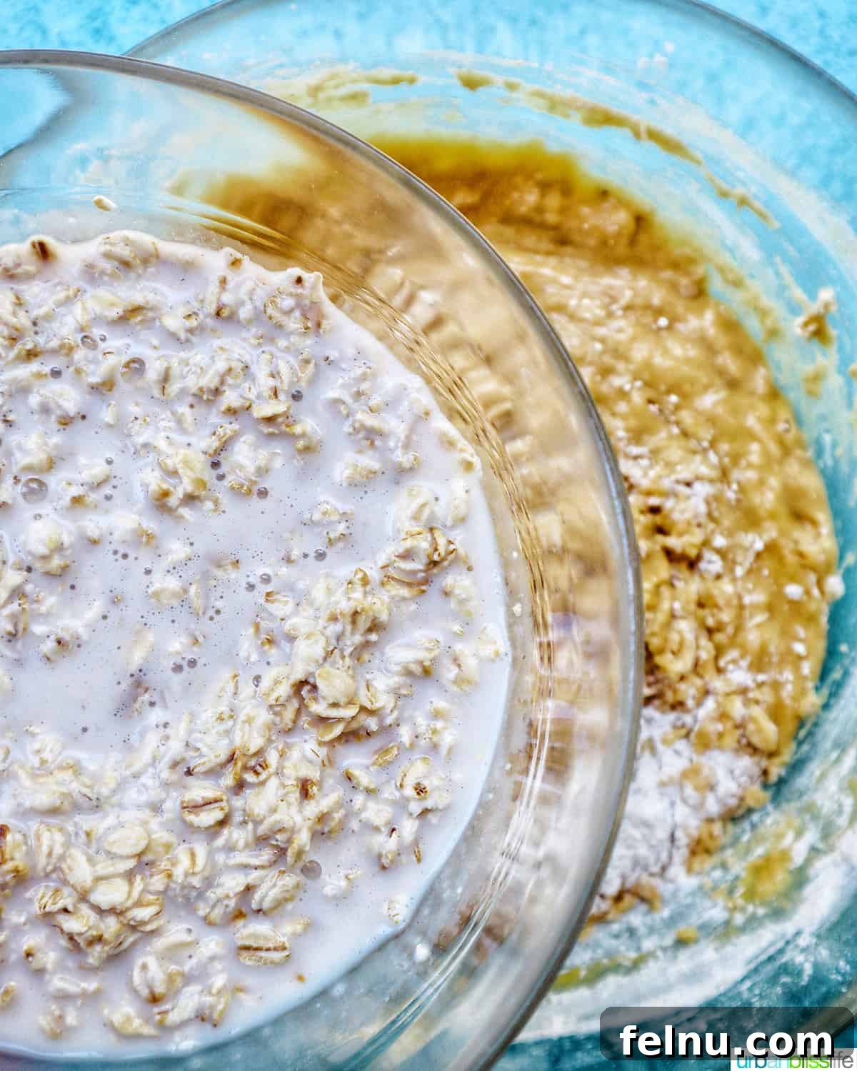 Bursting Blackberry Banana Oat Muffins 11 A bowl containing the milk and oatmeal mixture is positioned above a larger bowl of batter, ready to be folded in.