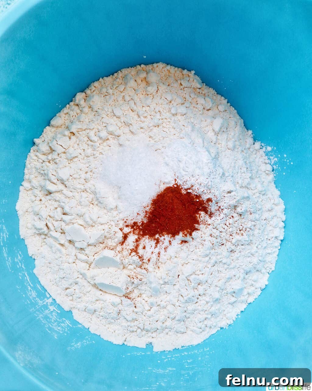 Bursting Blackberry Banana Oat Muffins 6 Dry ingredients like flour, baking powder, baking soda, salt, and cinnamon are whisked together in a blue mixing bowl.