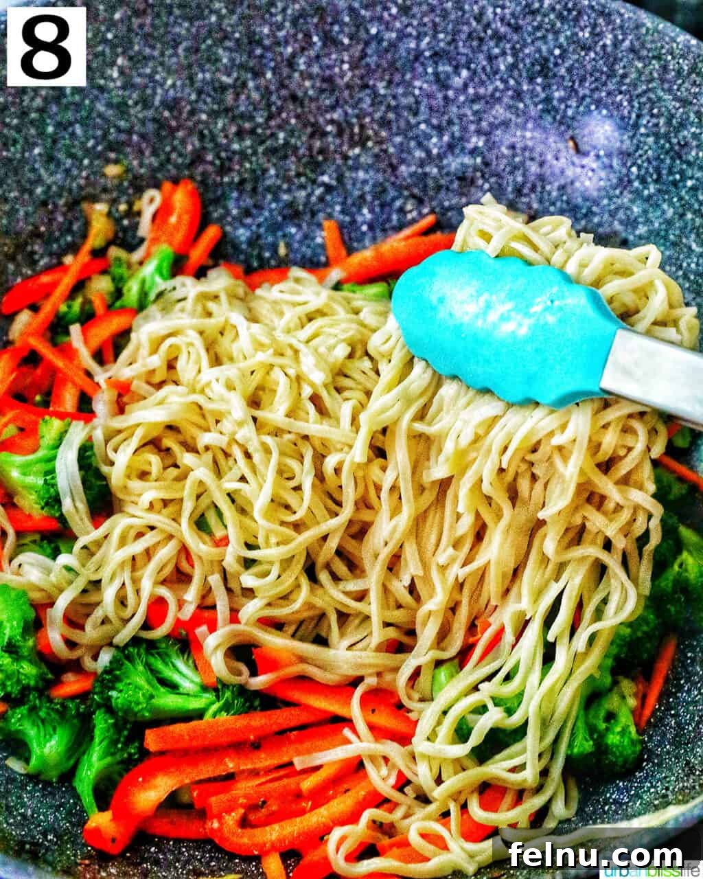Homemade Prawn Chow Mein Delight 15 Tongs tossing parboiled noodles with stir-fried vegetables in a wok, combining the ingredients.