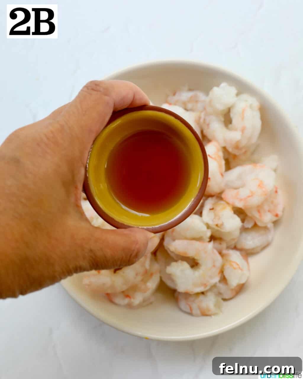 Homemade Prawn Chow Mein Delight 8 A hand adding a pinch of paprika (or similar spice) to the seasoned prawns in a bowl.