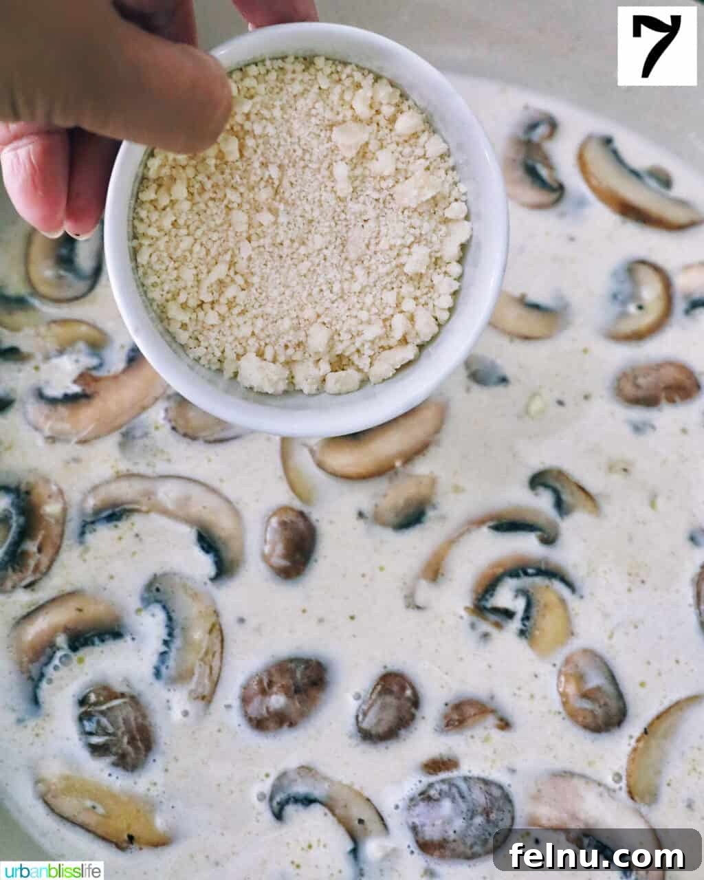 Earthy Mushroom Pesto Pasta 12 Sprinkling grated parmesan cheese over the creamy mushroom sauce in a pan.