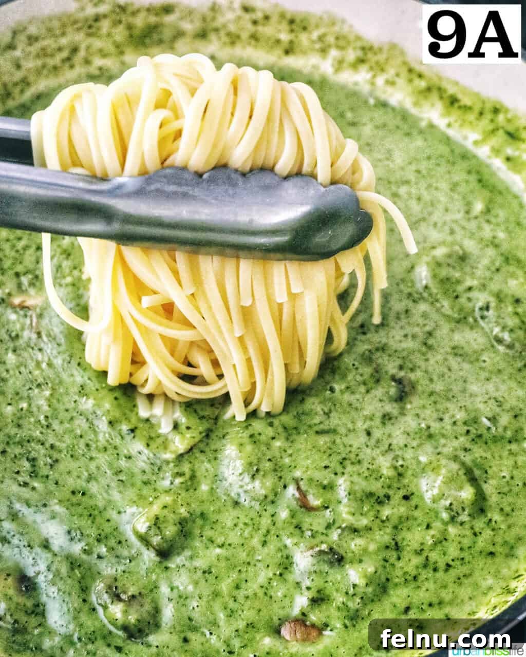 Earthy Mushroom Pesto Pasta 14 Kitchen tongs lowering cooked linguine pasta into the creamy mushroom pesto sauce in a pan.