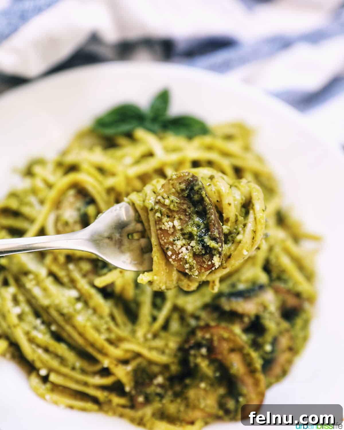Earthy Mushroom Pesto Pasta 3 Fork twirling linguine pasta coated in creamy pesto sauce with tender mushrooms.