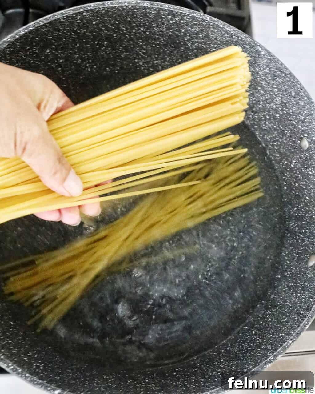 Earthy Mushroom Pesto Pasta 5 Hand lowering linguine pasta into a large pot of boiling water.