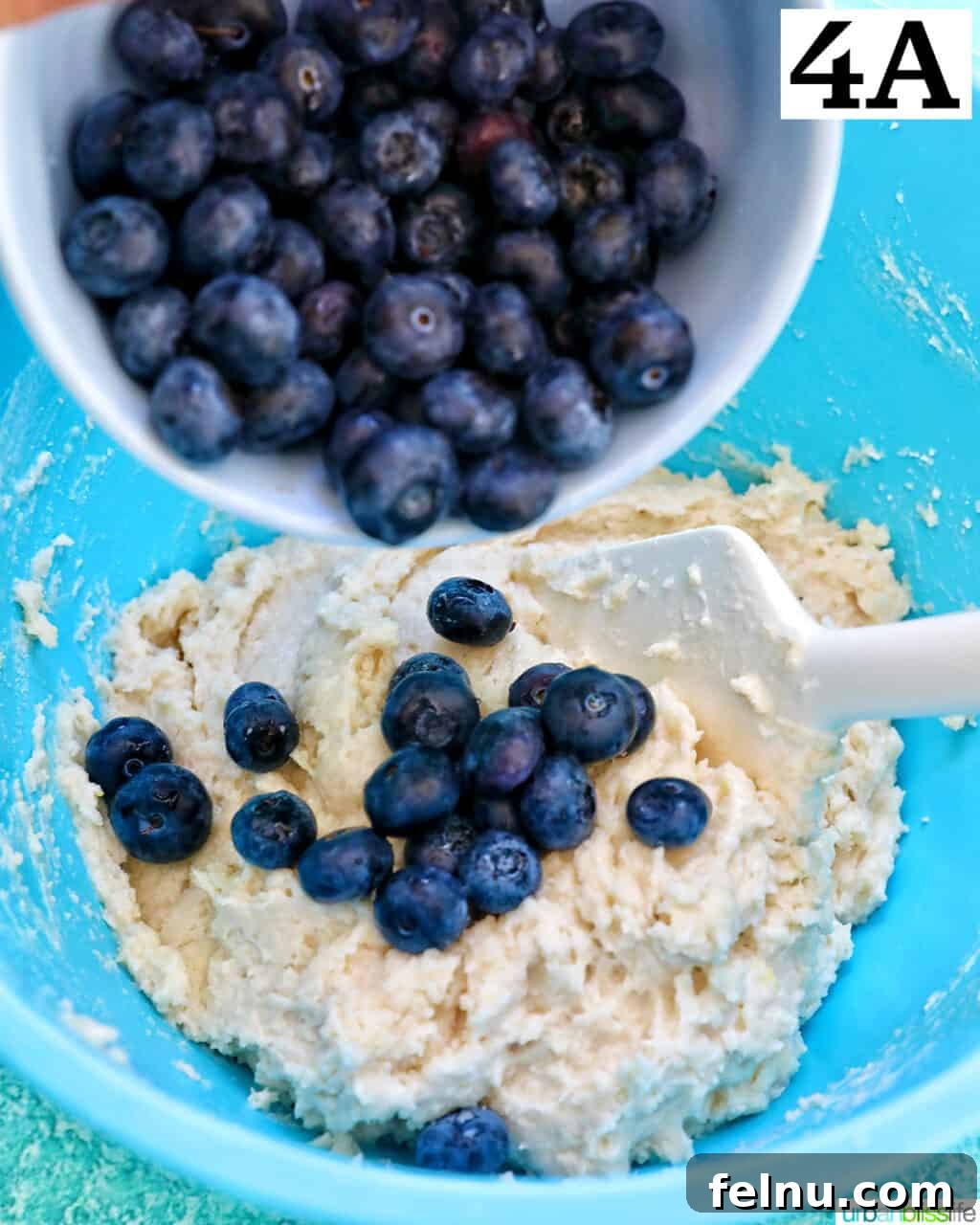 Lemon Blueberry Bliss Cookies 11 Pouring blueberries into dry batter ingredients to make lemon blueberry cookies.