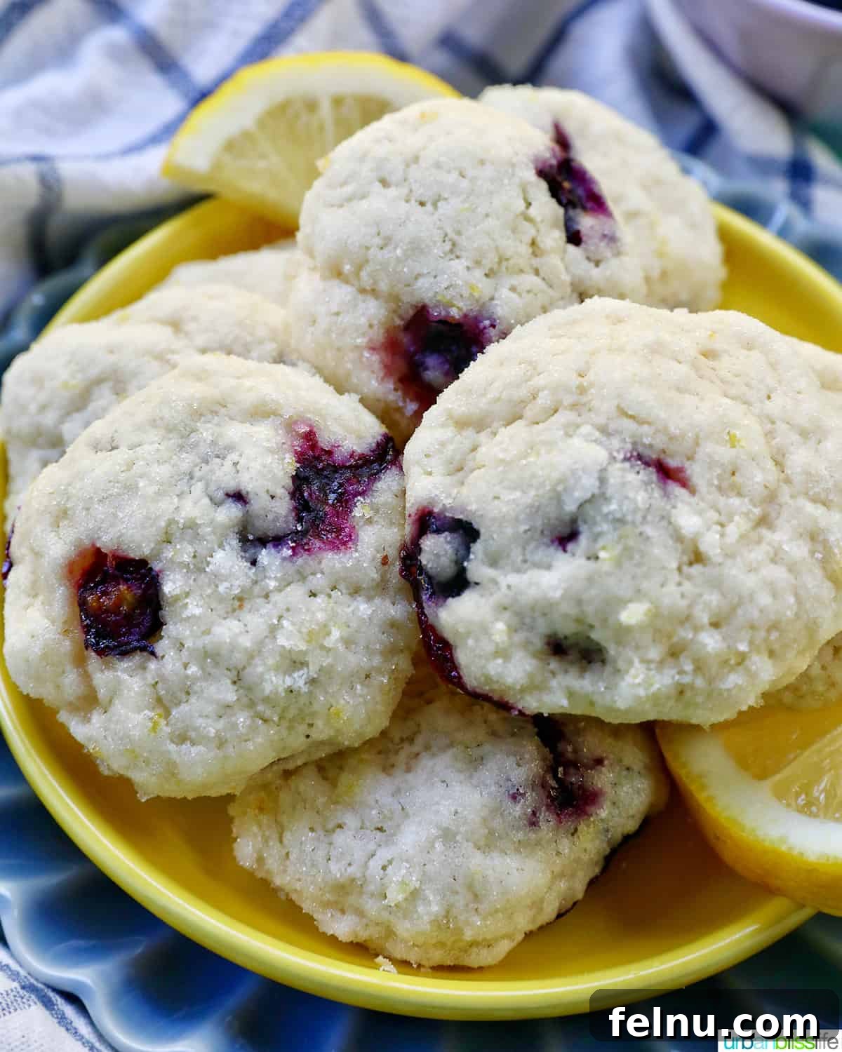 Lemon Blueberry Bliss Cookies 3 Lemon blueberry cookies on a yellow and blue plate with lemon slices.