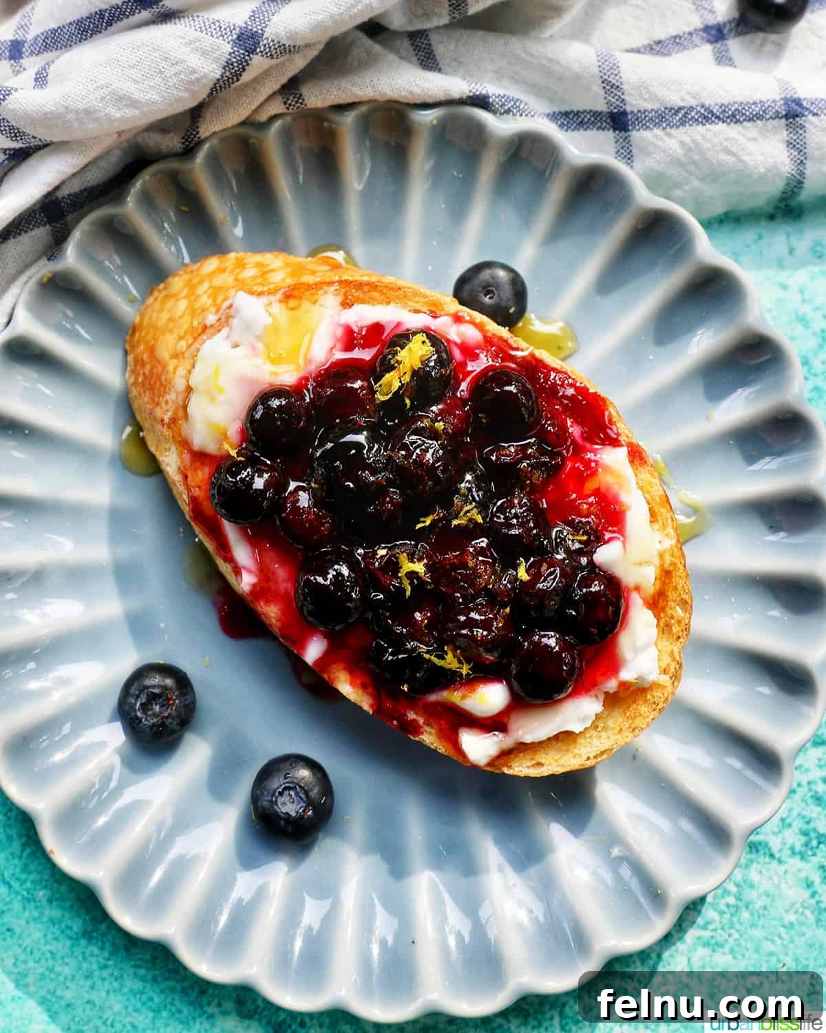 Blueberry Bliss Toast 2 Fresh blueberries and creamy cream cheese on golden brown toast, presented on a charming blue scalloped plate.