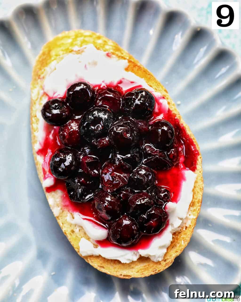 Blueberry Bliss Toast 12 Finished blueberry and cream cheese toast, garnished with lemon zest, on a blue scalloped plate.
