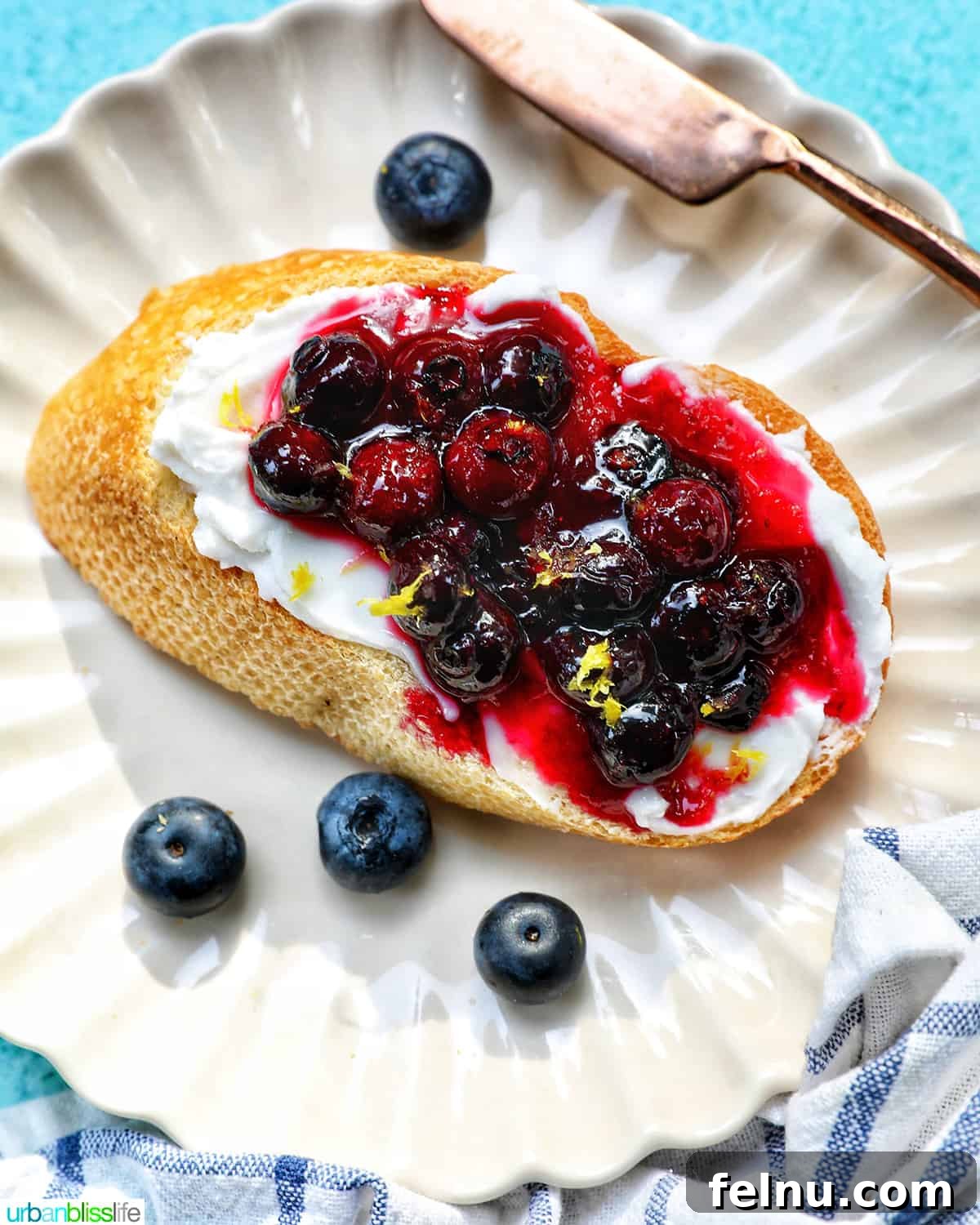 Blueberry Bliss Toast 13 Overhead shot of blueberry and cream cheese toast on a white scalloped plate.