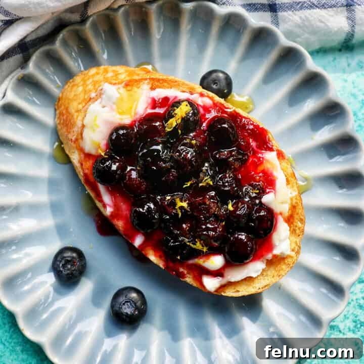 Vibrant blueberry and cream cheese toast on a blue scalloped plate, ready to be served.