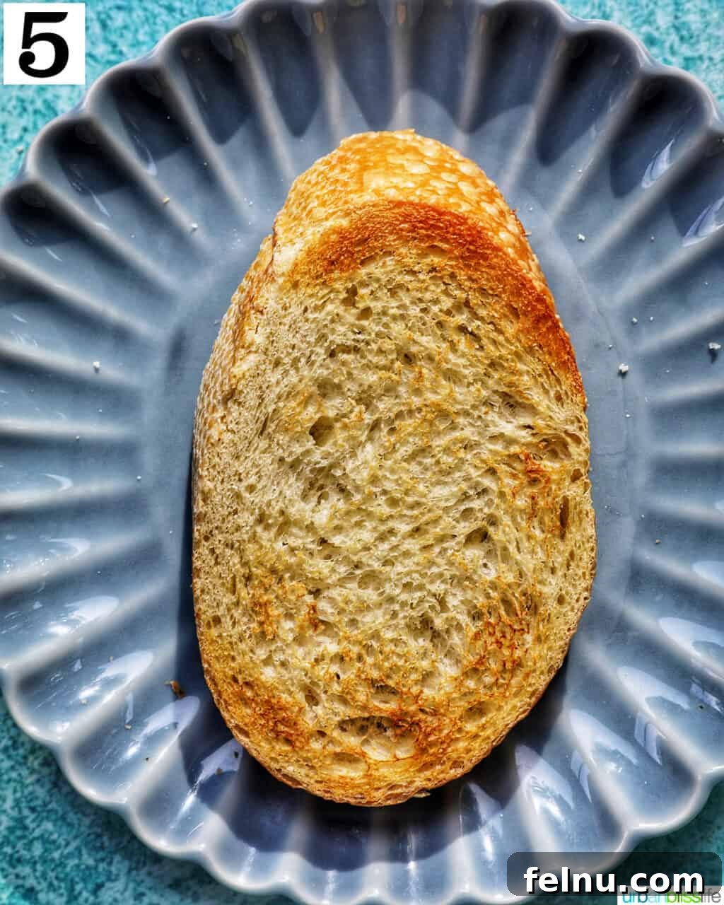Blueberry Bliss Toast 9 A perfectly toasted slice of bread resting on a blue plate, ready for toppings.