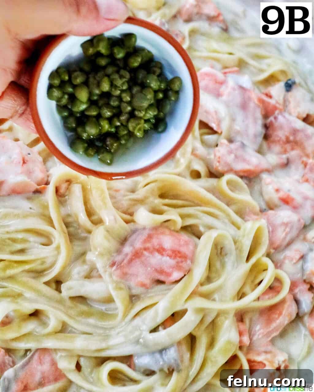 Velvety Salmon Pasta 17 A hand sprinkling capers over the salmon, pasta, and cream sauce in a skillet, adding a briny counterpoint.