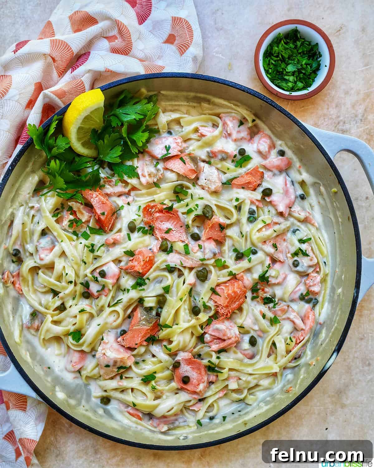Velvety Salmon Pasta 3 A large saucepan filled with creamy pasta alla salmone, generously garnished with fresh parsley and delicate lemon slices, ready to be served.