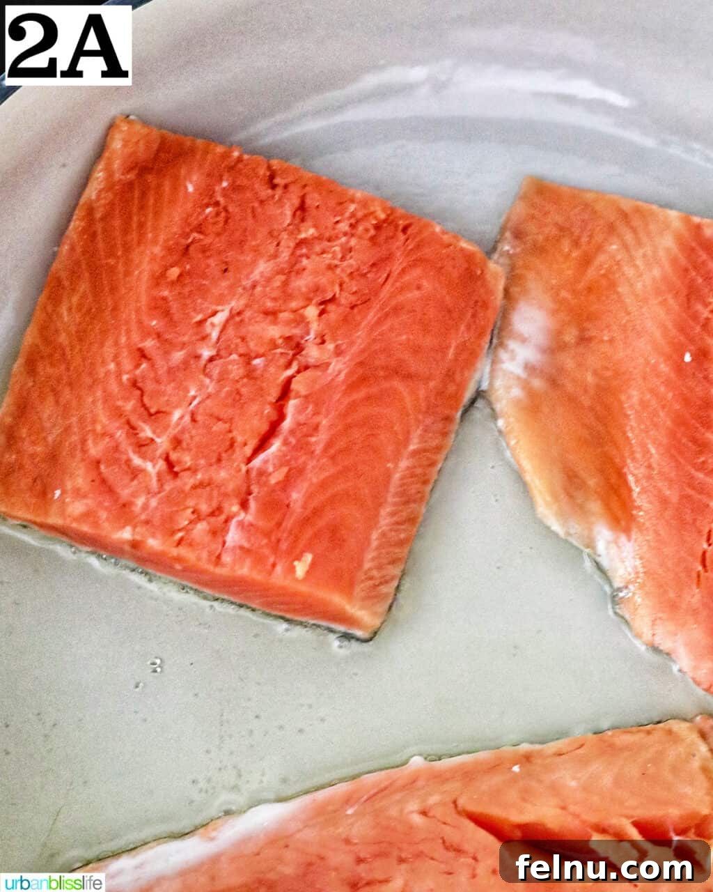 Velvety Salmon Pasta 6 Uncooked salmon fillets beginning to sear in a large white skillet, showing a slight browning.