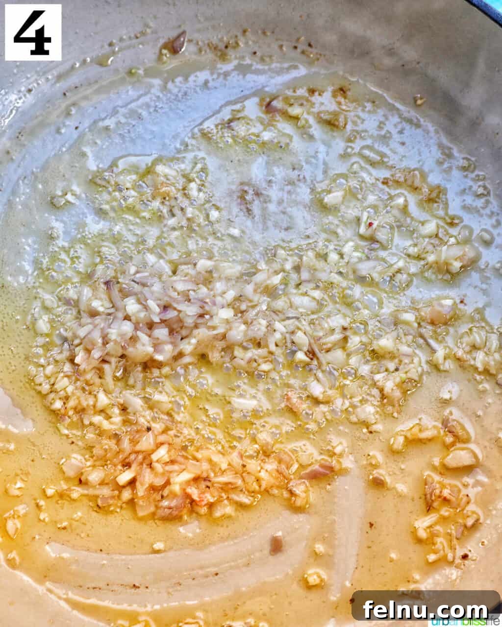 Velvety Salmon Pasta 9 Minced garlic gently sautéing in melted butter within a white skillet, releasing its fragrant aroma.