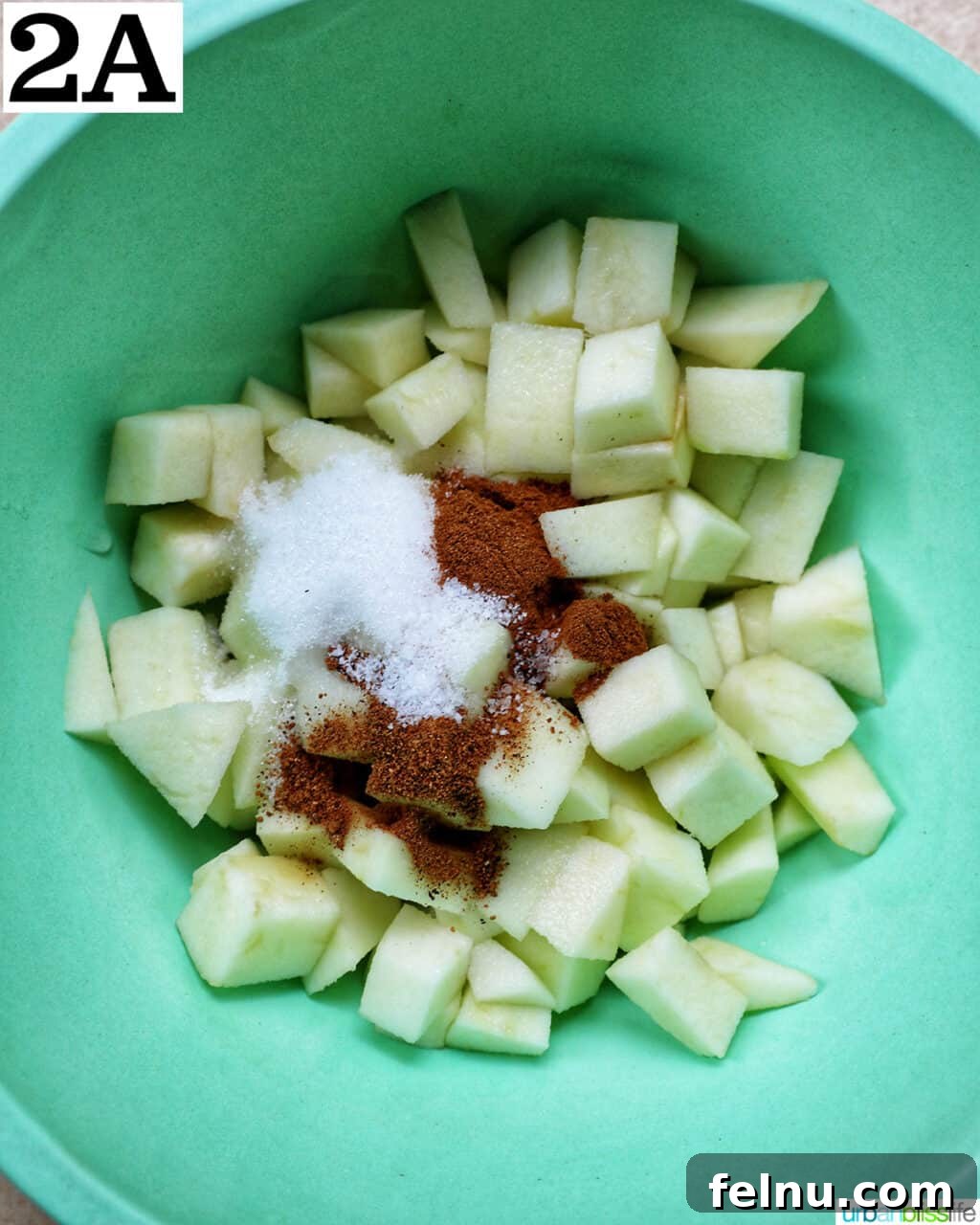 Air Fryer Apple Crumble 6 Green bowl with diced apples and spices.