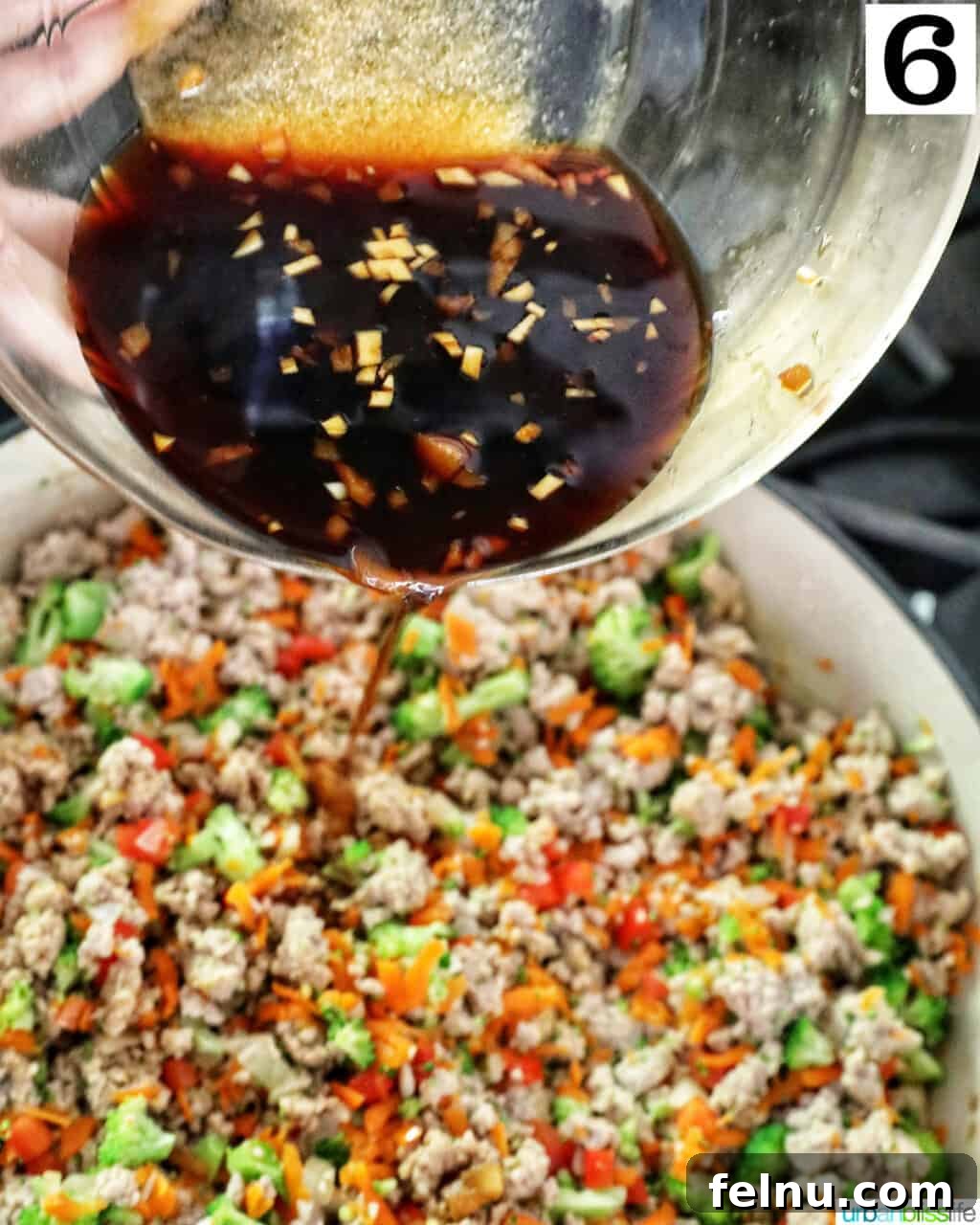 Flavorful Teriyaki Ground Turkey Stir-Fry 12 The prepared teriyaki sauce being poured evenly over the cooked ground turkey and vegetables in the skillet, ready to be tossed and coated.