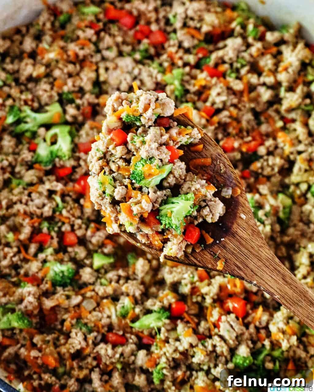 Flavorful Teriyaki Ground Turkey Stir-Fry 13 A serving spoon lifting a spoonful of ground turkey teriyaki from a brown rice bowl, showcasing the blend of meat and colorful vegetables.