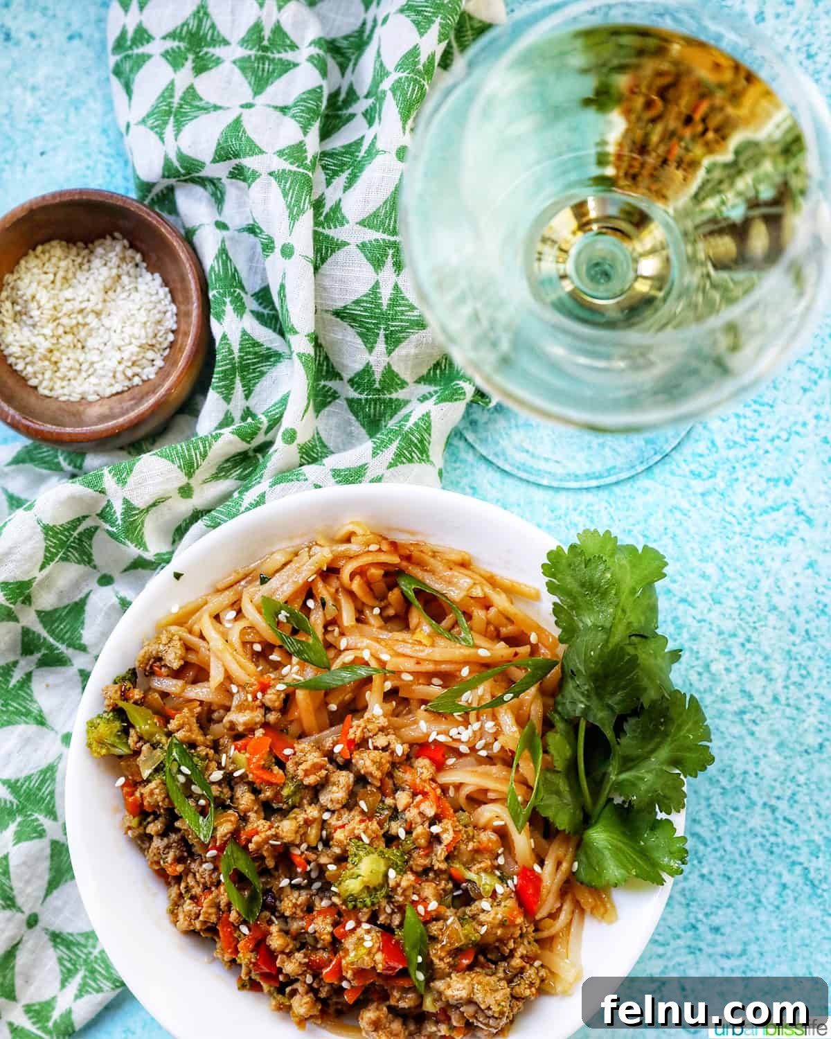Flavorful Teriyaki Ground Turkey Stir-Fry 17 Ground Turkey Teriyaki with green onions, broccoli, carrots, and red bell peppers, in a white bowl with cilantro garnish, alongside a glass of crisp white wine.