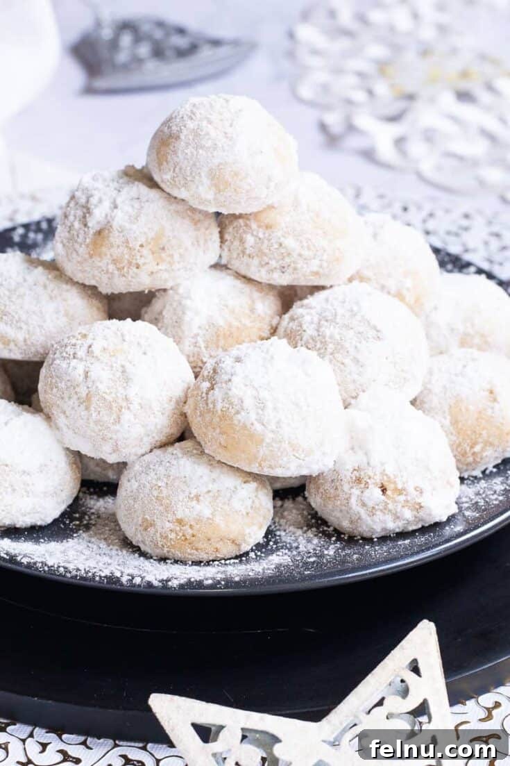 A pile of easy vegan snowball cookies, coated in powdered sugar.