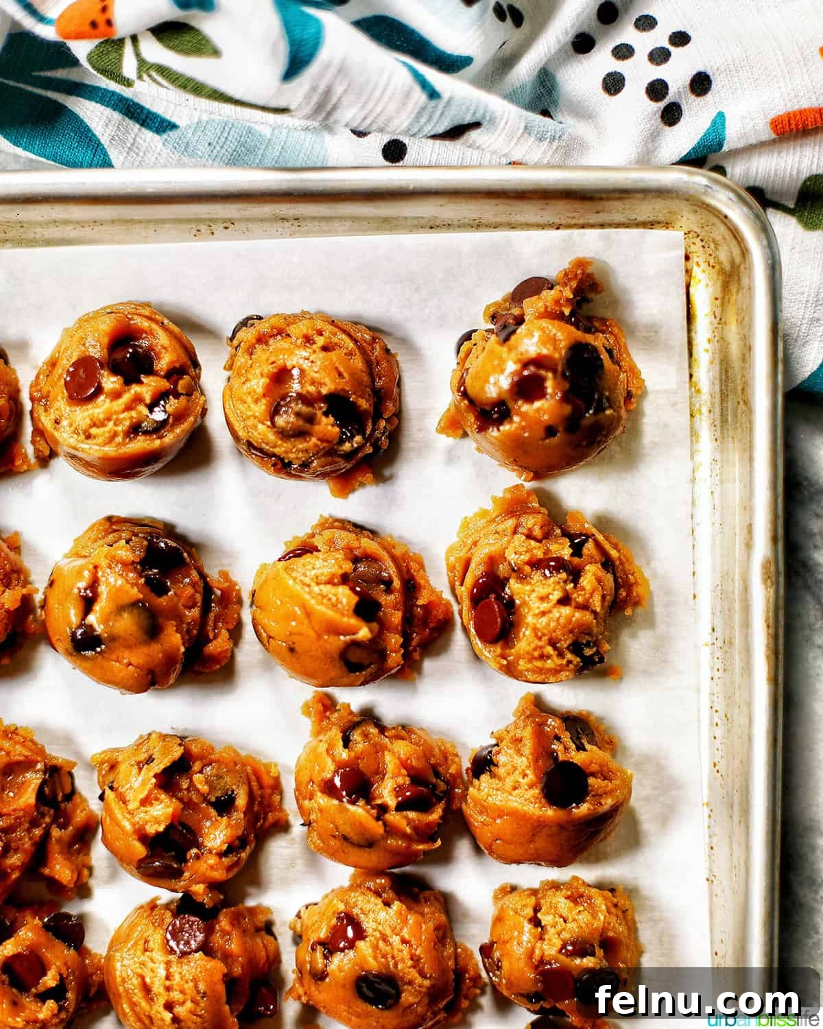 32 Irresistible Vegan Christmas Cookies 6 Scoops of brown butter chocolate chip cookie dough perfectly arranged on a baking sheet, ready for the oven.