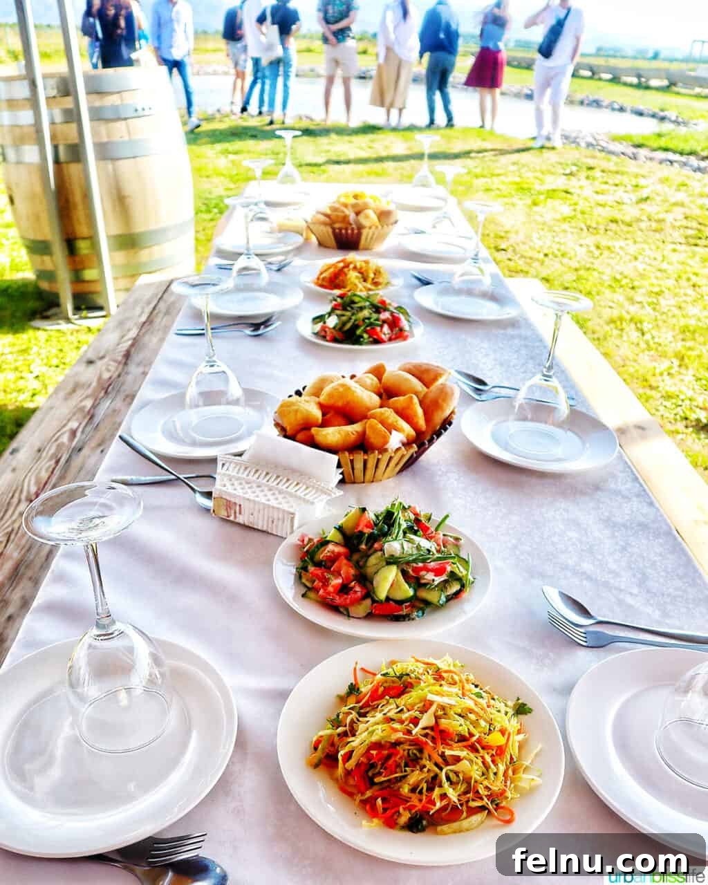 Kazakhstan Wine: A Journey Through Time and Taste 12 Table set with several dishes for a vineyard dinner and people in the background at Arba Winery near Almaty, Kazakhstan.