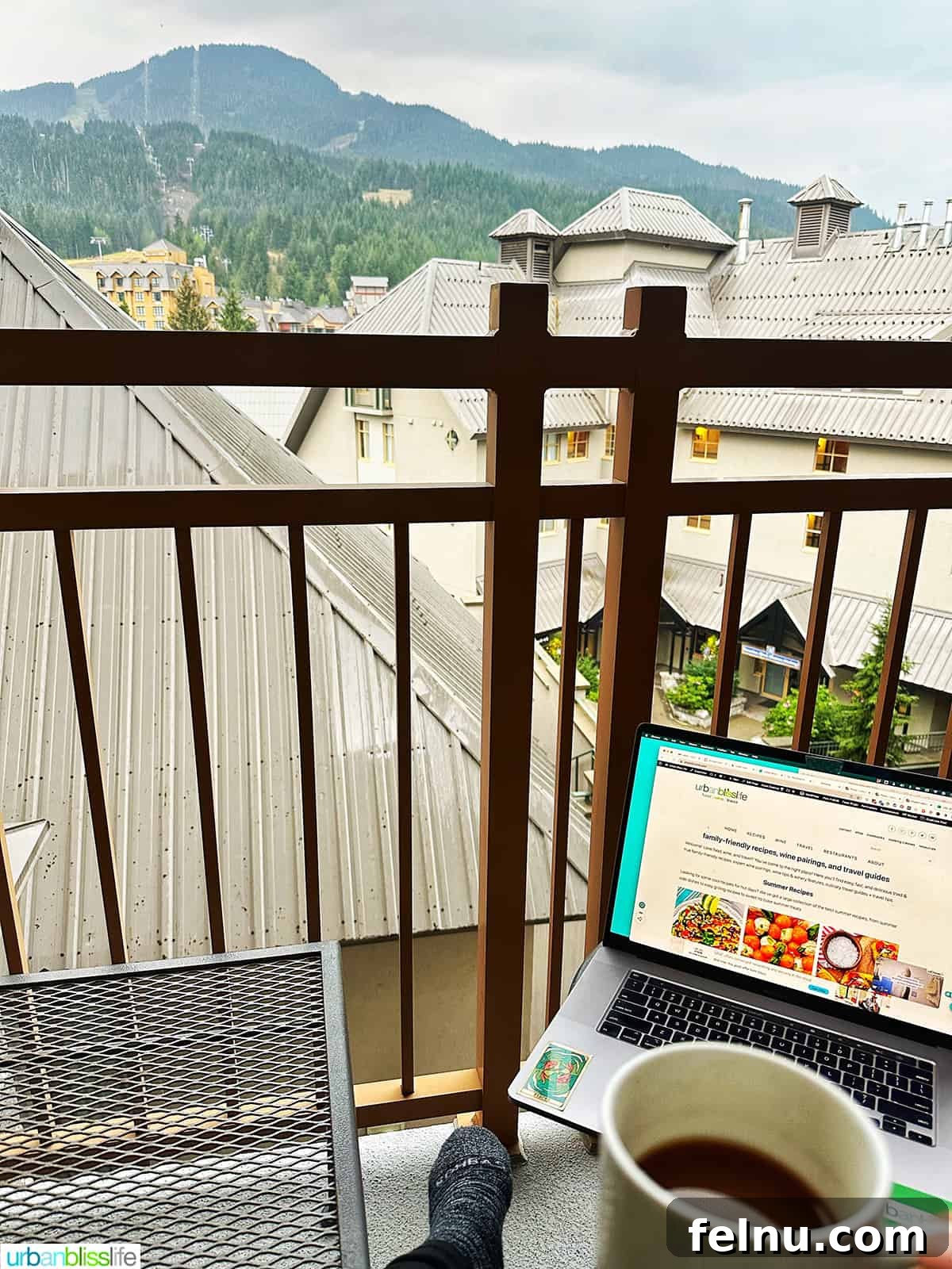 Whistler Village Signature Escape 11 Laptop and coffee cup placed on a table on a private balcony, overlooking Whistler Village, from a suite at Pan Pacific Whistler Village Centre Hotel, perfect for remote work or relaxation.