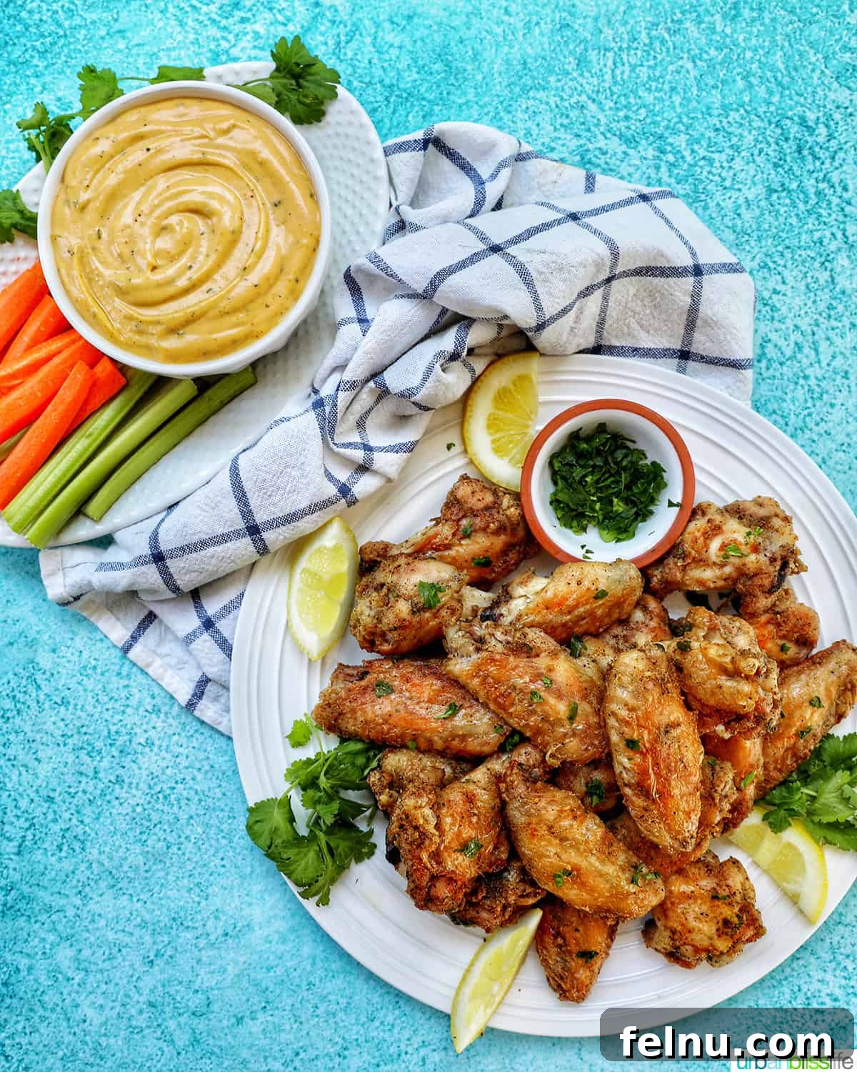 Ultimate Crispy Salt and Pepper Wings 12 white plate full of salt and pepper wings with side of chopped fresh parsley and lemon wedges, and bowl of buffalo ranch sauce with carrots and celery.