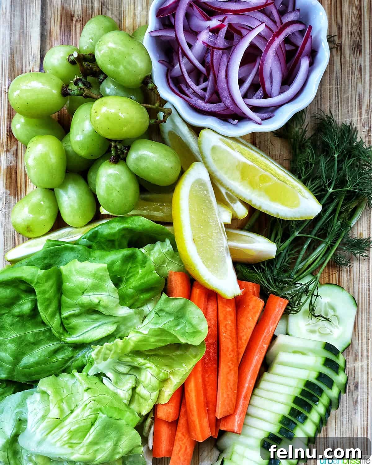 Variety of fresh vegetables perfect for a seacuterie board including carrots, lettuce, grapes, onions, and cucumbers.